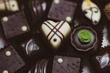 Chocolate candy full frame. White chocolate heart shaped candy on chocolate candy background