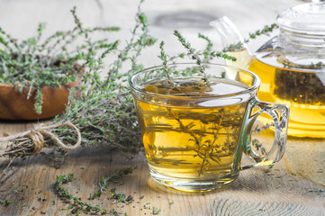 glass cup of healthy herbal thyme tea with fresh thyme leaves bunch on wooden rustic background, hot drink thymus vulgaris - obrazy, fototapety, plakaty