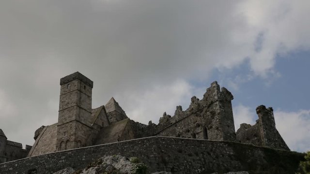 Looking up at the ancient stone building of Cormac's Chapel at Rock of Cashel in Ireland. Historic location filled with legend and mystery. Time lapse view of clouds passing over a castle.