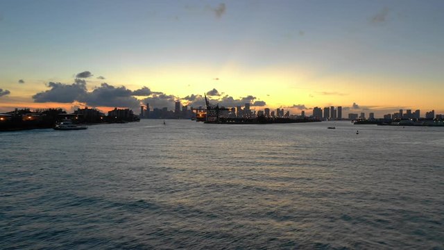 Low Miami aerial with yacht speeding under. Approaching Port of Miami at sunset 4k