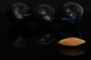 Group of two whole fresh purple plum with one drupe isolated on black glass