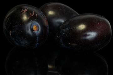 Group of three whole fresh purple plum isolated on black glass