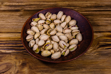 Ceramic plate with pistachio nuts on a wooden table