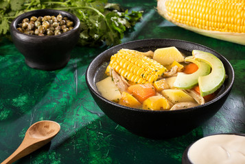 Traditional Colombian ajiaco served on black ceramic dish