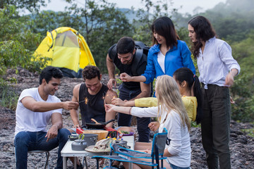 Group of friends go camping in the forest, have a picnic, cook dinner, set a fire on the evening to celebrate in holiday