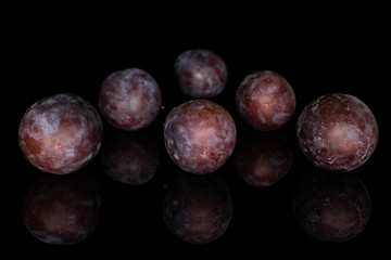 Group of five whole sweet purple plum triangle isolated on black glass