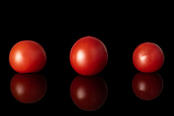 Group of three whole fresh red tomato isolated on black glass