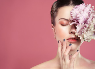 Fototapeta na wymiar beautiful young woman with makeup in gentle colors holds a big pink flower, beauty concept