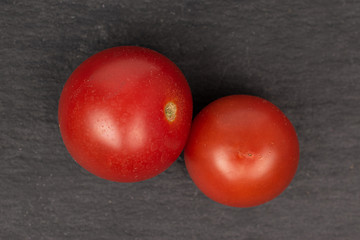 Group of two whole fresh red tomato flatlay on grey stone