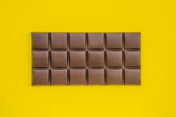 Tasty chocolate bar on a yellow background