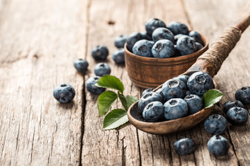 Blueberries in wooden spoon on old wood table. Healthy eating and nutrition concept.