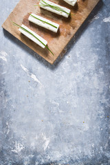 Feta cheese cut in pieces with chives on a wet cutboard,flat lay top view image