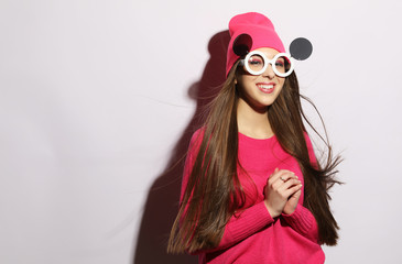 young woman wearing pink clothes listening to music in headphones on white background