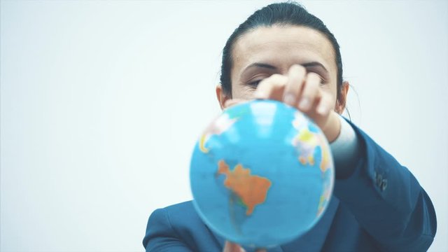 Portrait of a cute and happy female teacher on a white background. During this time, the globe holds on its elongated hands. Close-up.