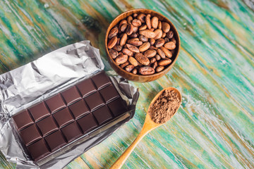 Chocolate and cocoa beans on color wooden background