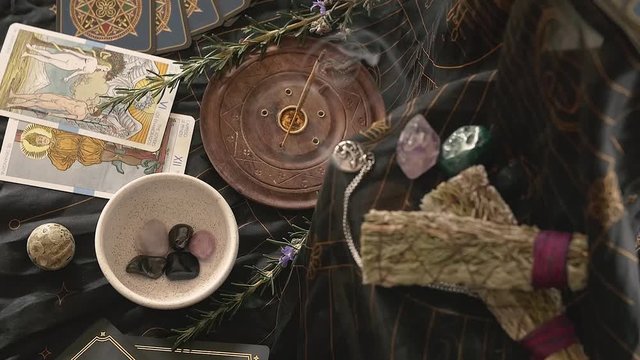 Slow zoom into altar with incense and hands placing crystals into frame