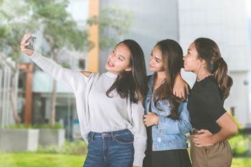 Group of pretty girls take a selfie photo in park