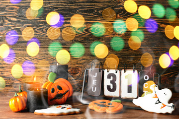 Composition with creative Halloween cookies, candles and calendar on wooden background