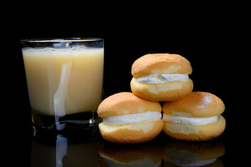 side view cakes with cream filling with cup of soy milk on black background