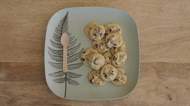 Zoom in as and places chocolate chip cookie on plate