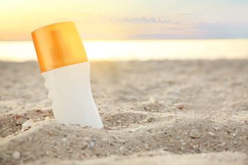 Bottle of sunscreen cream on sea beach