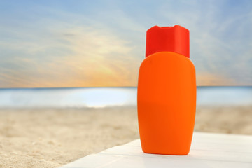 Bottle of sunscreen cream on sea beach