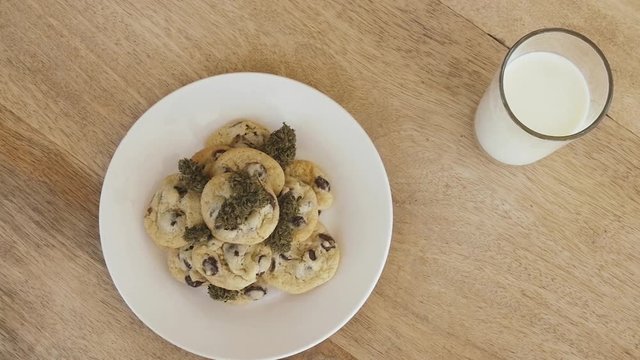 Pan across glass of milk and space cookies on wooden table and white plate
