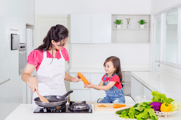 Little girl helping her mother cook in the kitchen