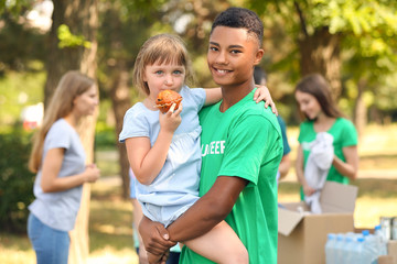 African-American volunteer with poor little girl outdoors