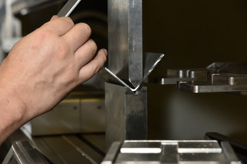 worker operating metal press machine at workshop.