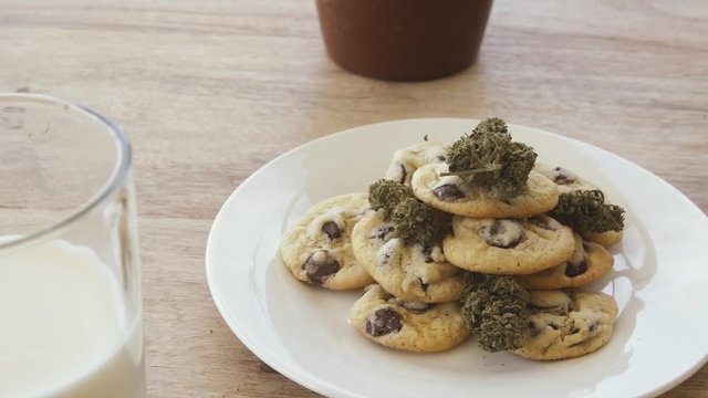 Track and focus shift from glass of milk to plate of chocolate chip space cookies on a white plate
