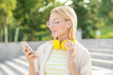Beautiful young woman with headphones and mobile phone outdoors