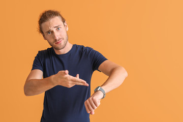 Stressed man with watch on color background