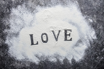 Word LOVE and white flour on grunge background