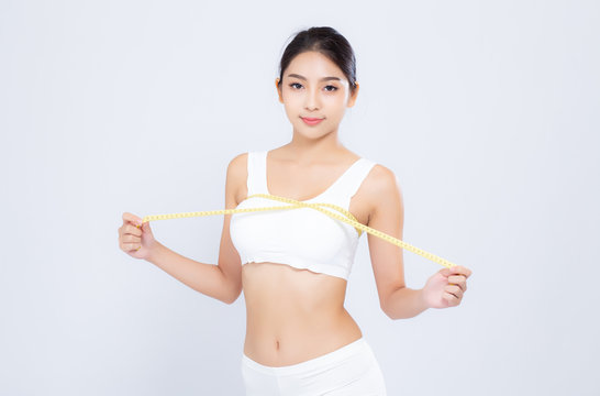 Beautiful portrait asian woman diet and slim with measuring breast and augmentation isolated on white background, girl have cellulite loss with tape measure, health and wellness concept.