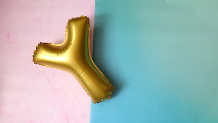 A golden balloon with the letter 'Y', on a pink and blue background.