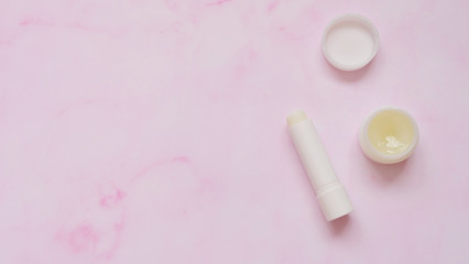 Top view of a tube of white lip balm and a small round container of solid perfume.