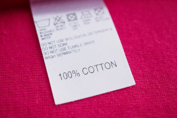 White laundry care washing instructions clothes label on red cotton shirt