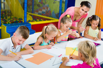 Fototapeta premium Kids drawing together with tutor at hobby group
