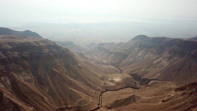 Aerial footage Over Judea Desert And Dead sea in the background Drone view of Large wadi with desert mountains and Dead sea in the background
