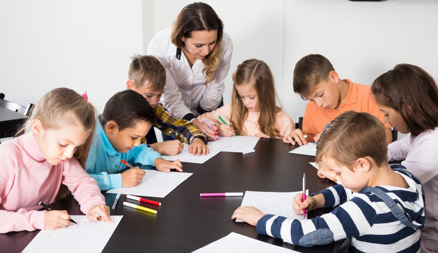 Teacher and elementary age kids drawing at classroom
