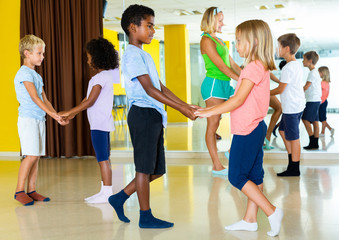Positive little boys and girls dancing pair dance in the ballet studio