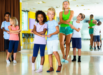 Group of children practicing vigorous jive movements in dance cl