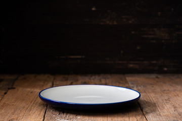 Empty plate on dark black wooden background. Side view.