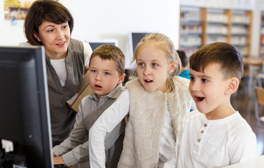 Fototapeta na wymiar Female teacher giving lesson to kids in computer class