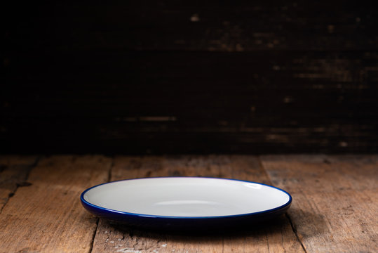 Empty Plate On Dark Black Wooden Background. Side View.