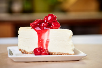 a slice of cherry cheesecake on a kitchen countertop - obrazy, fototapety, plakaty