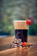 a glass of dark beer with chocolate and strawberries