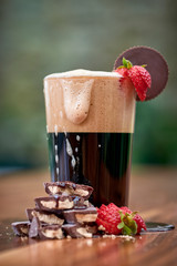 a glass of dark beer with chocolate and strawberries