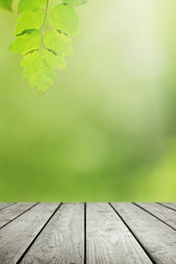 Naklejka na ściany i meble Wooden table and blurred green leaf nature in garden background. 